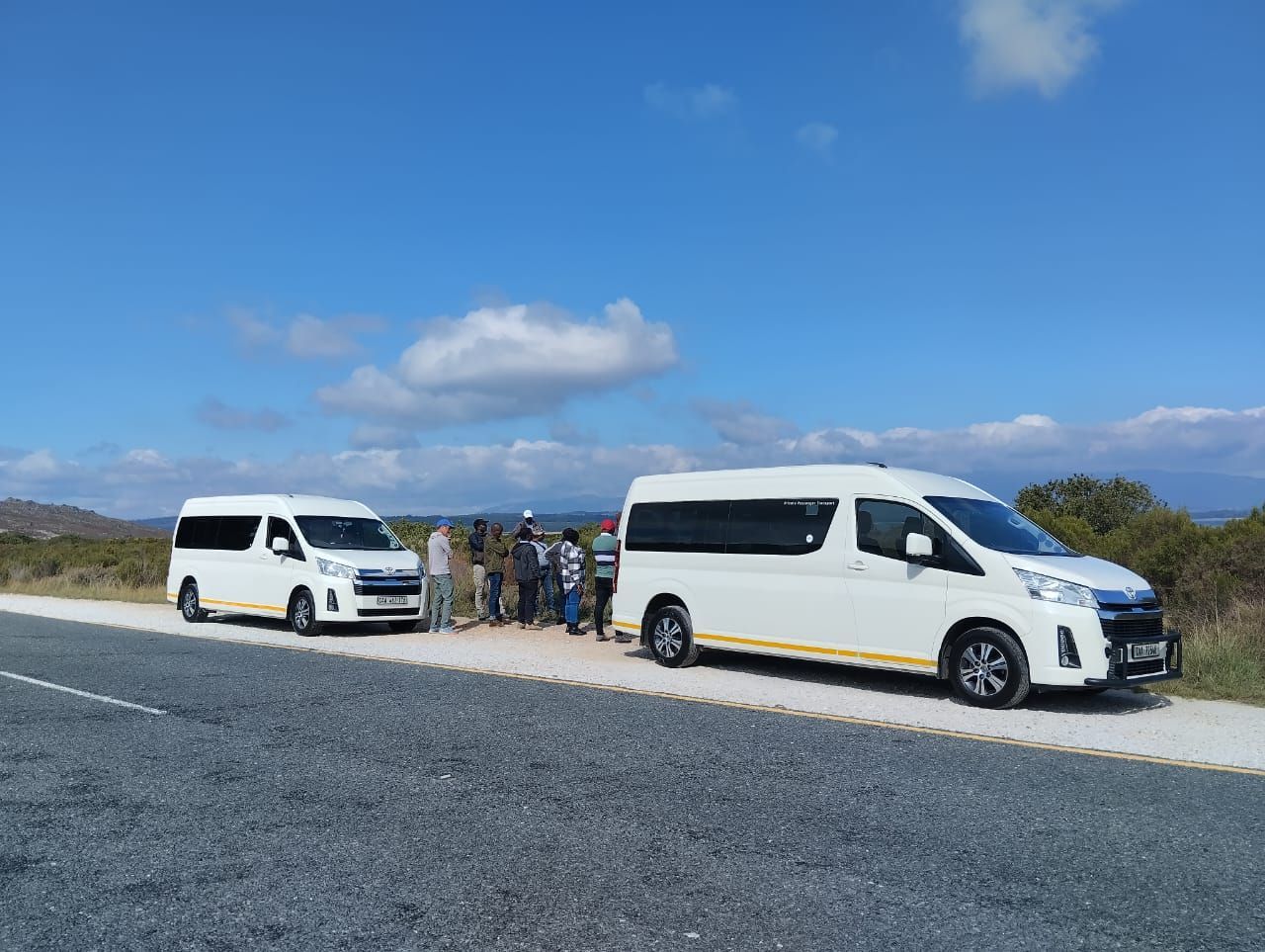 Two white vans are parked next to each other on the side of the road.