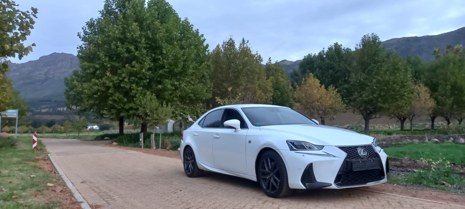 A white car is parked on the side of a dirt road.