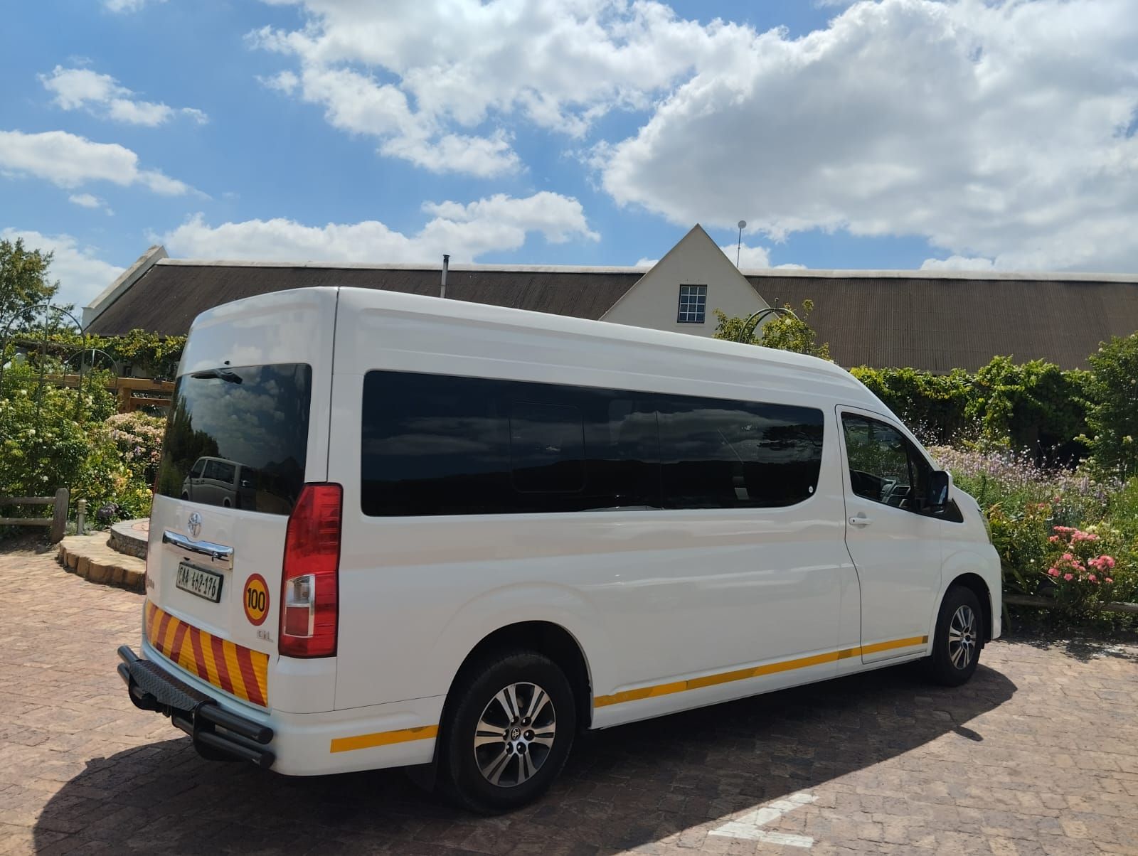 A white van is parked on a brick driveway in front of a house.
