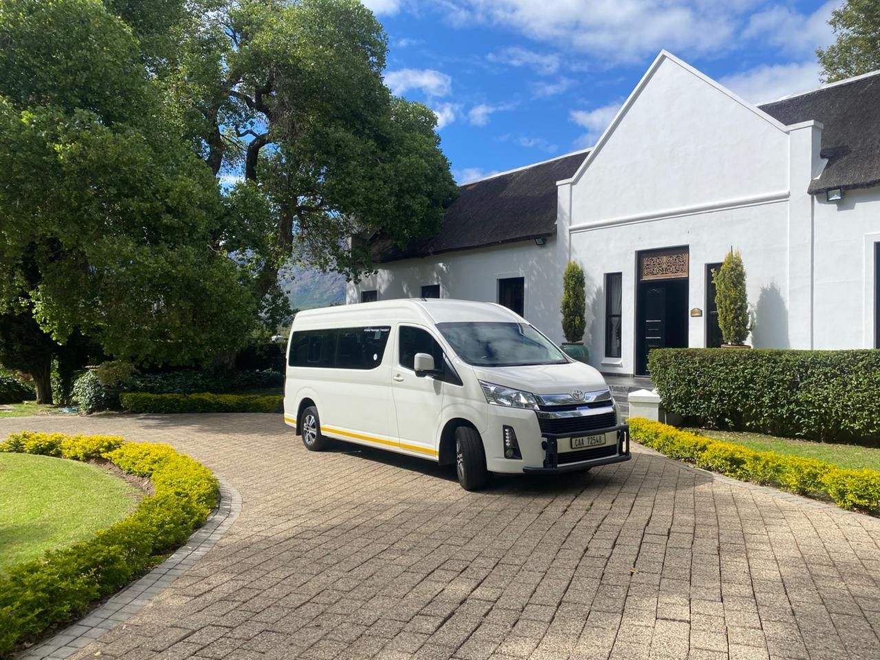 A white van is parked in front of a white house.