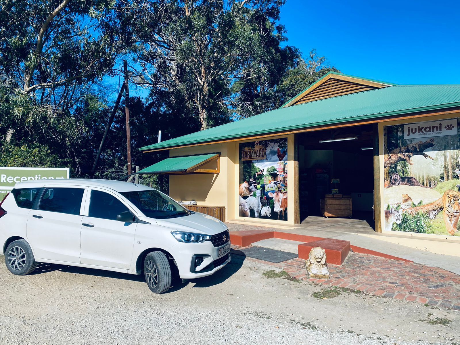 A white car is parked in front of a building with a green roof.