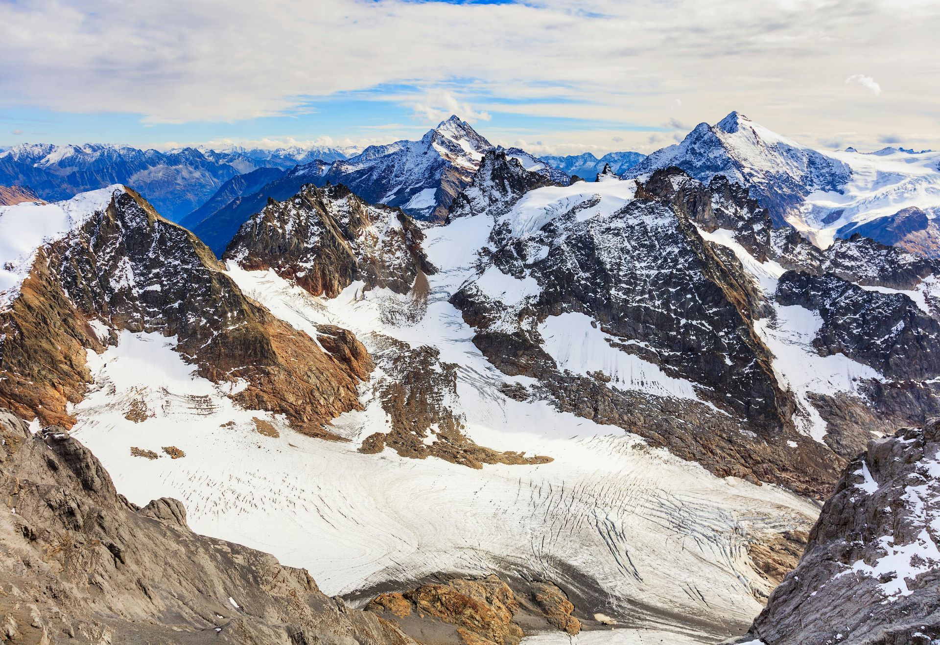 An aerial view of a snowy mountain range with a glacier in the middle.