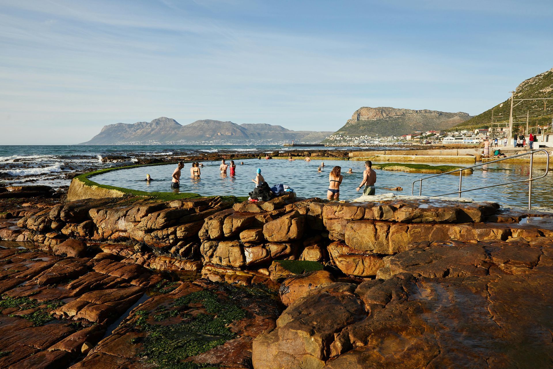 A group of people are swimming in a rocky pool near the ocean.