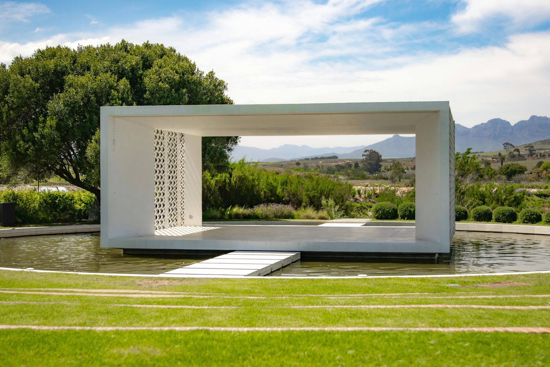 A white cube is in the middle of a lush green field