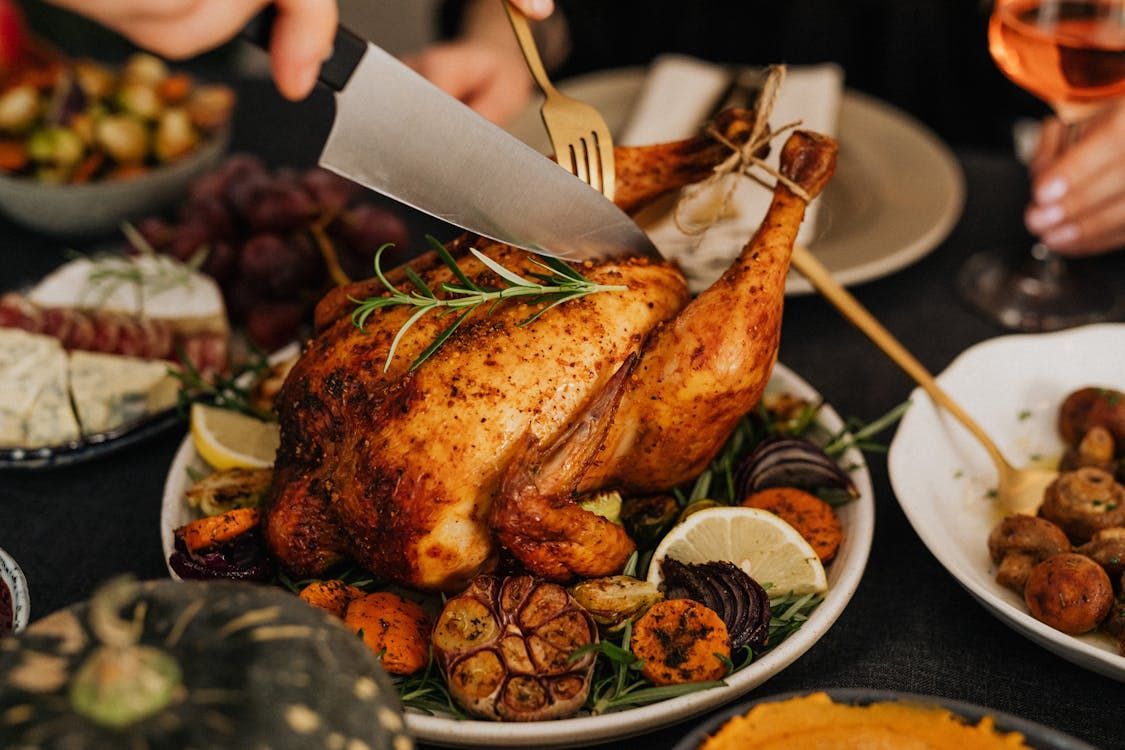 A person is cutting a roasted chicken on a plate.