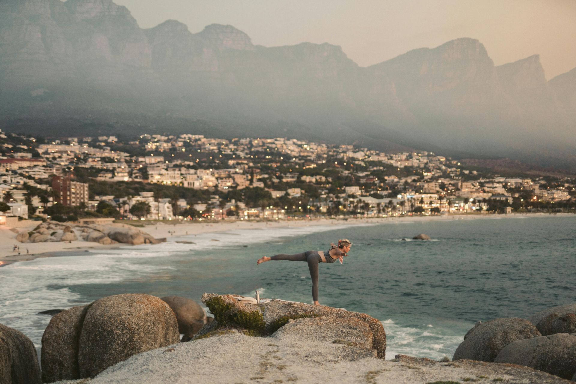 A person is doing yoga on a rock near the ocean.
