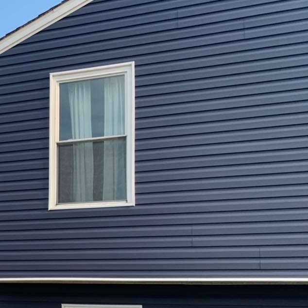 White-framed window on a blue vinyl-sided house exterior