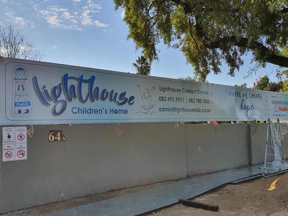 A lighthouse children 's home sign on a concrete wall.