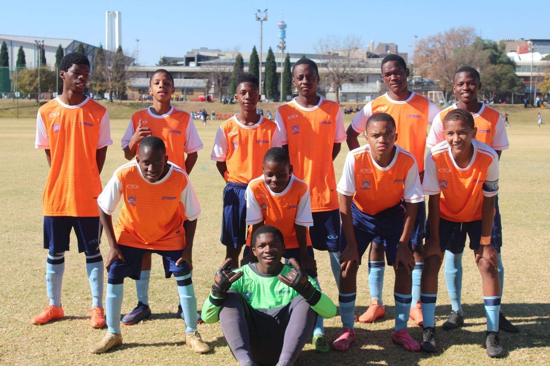 A group of soccer players are posing for a picture on a field