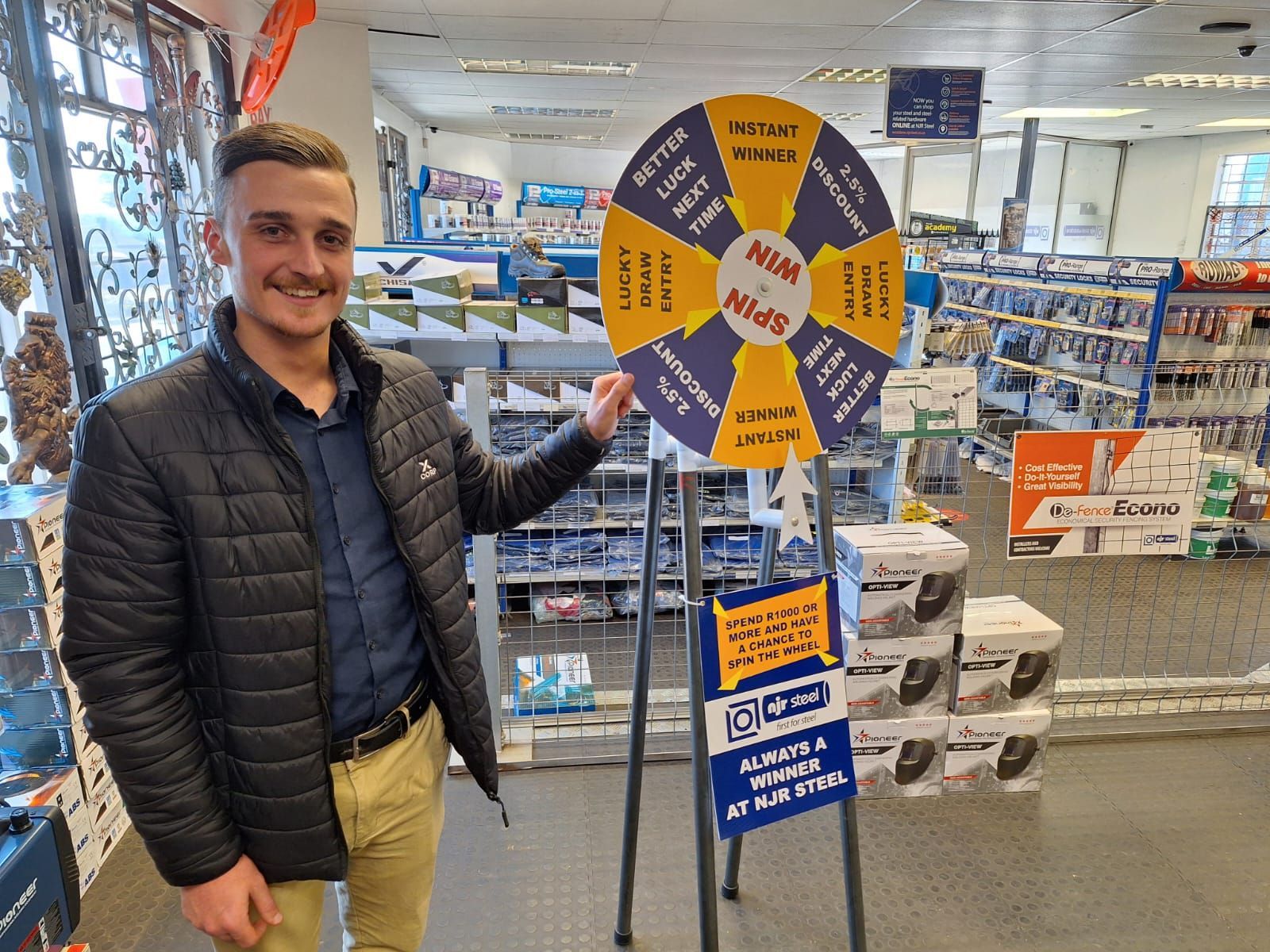 A man is standing in front of a spinning wheel in an NJR Steel Branch.