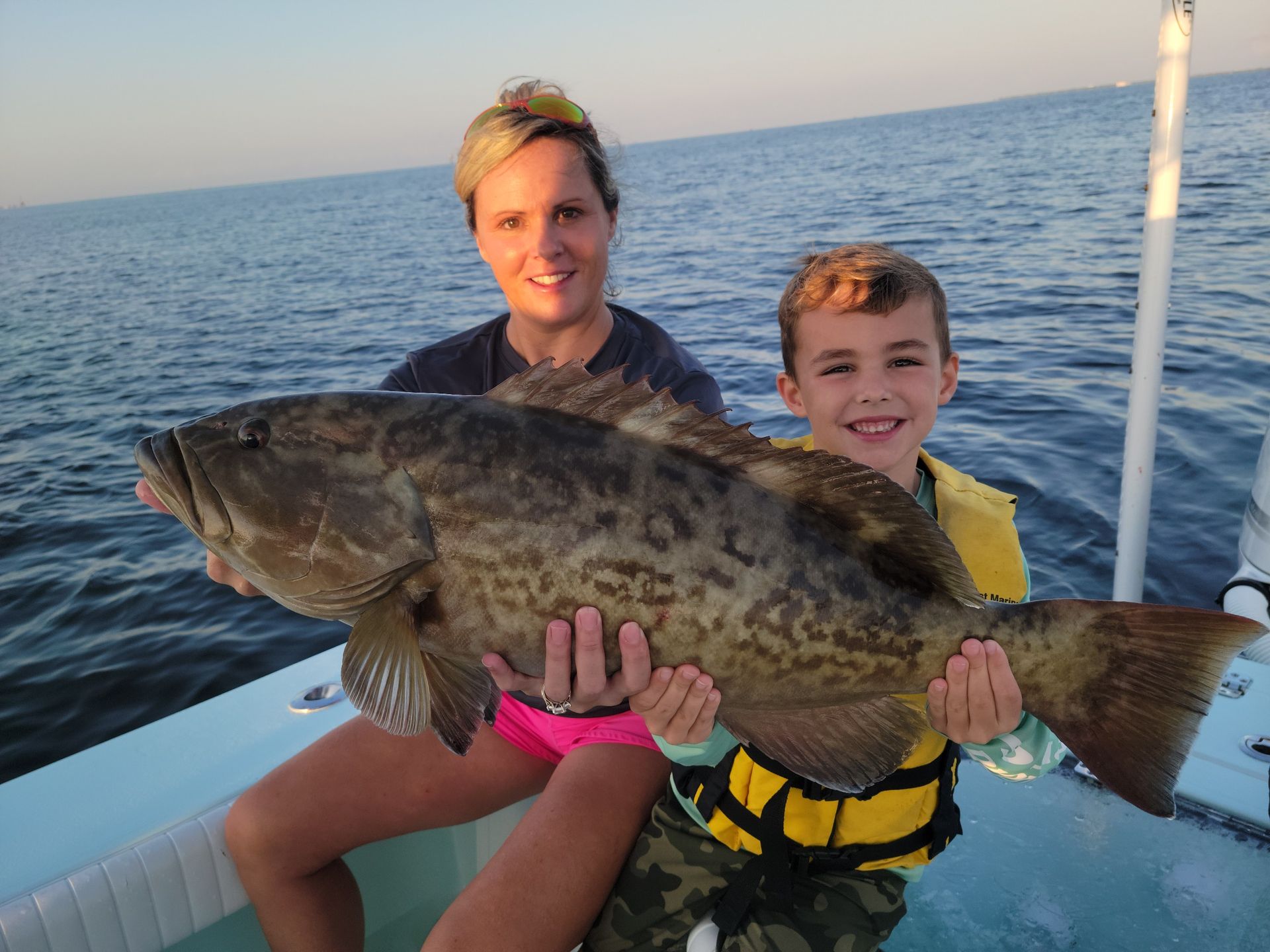 A man in a blue shirt is holding a large fish