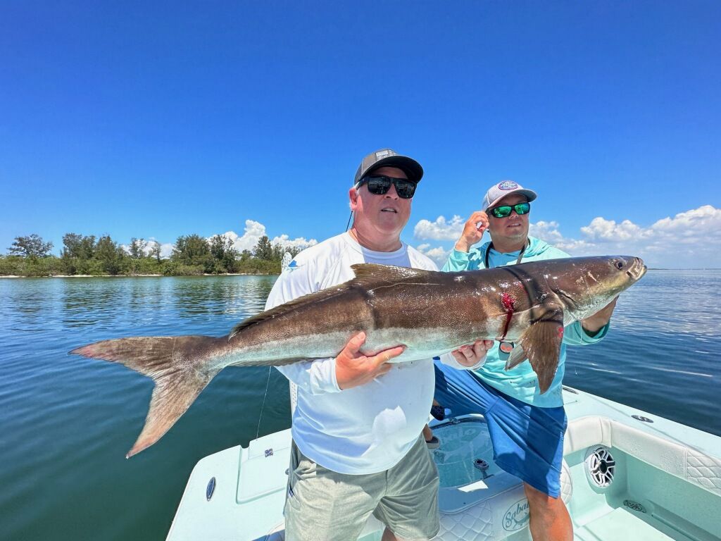 A man is holding a large fish on a boat.