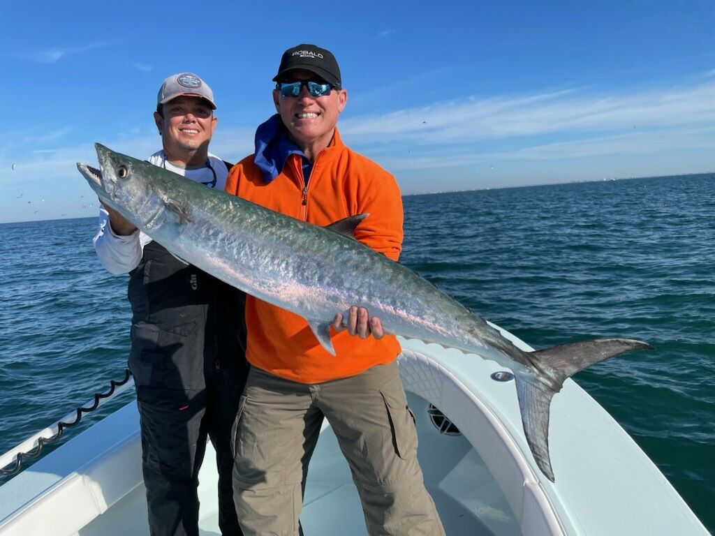 Two men holding a large fish on a boat