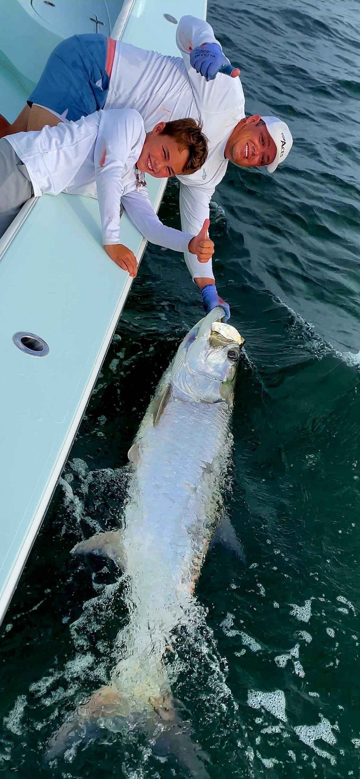 Two men are holding fish in their hands on a boat