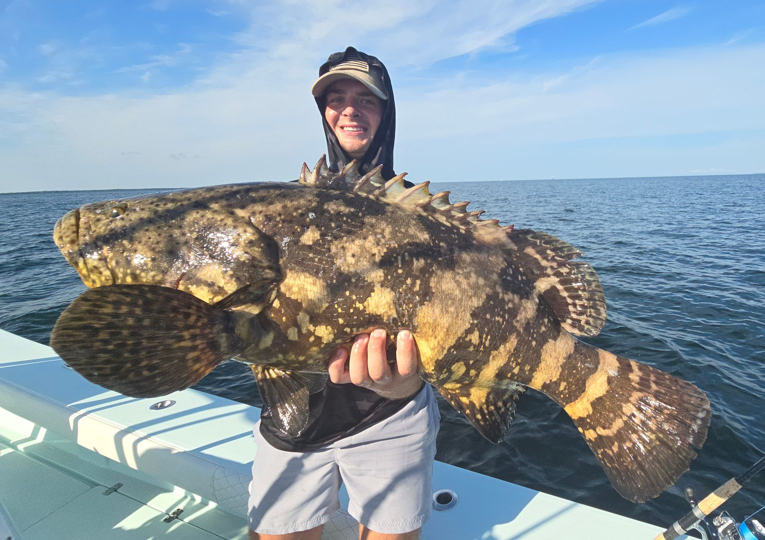Two men are holding a large fish in the water.