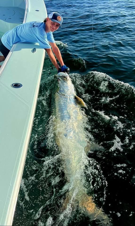 A man is holding a large fish in the water.