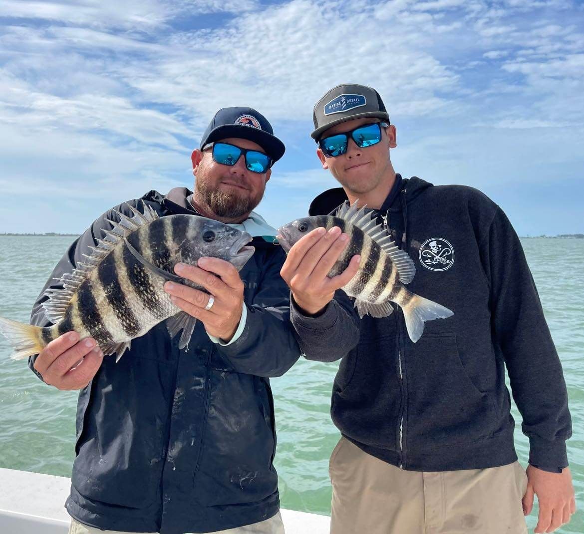 Two men are holding fish in their hands on a boat