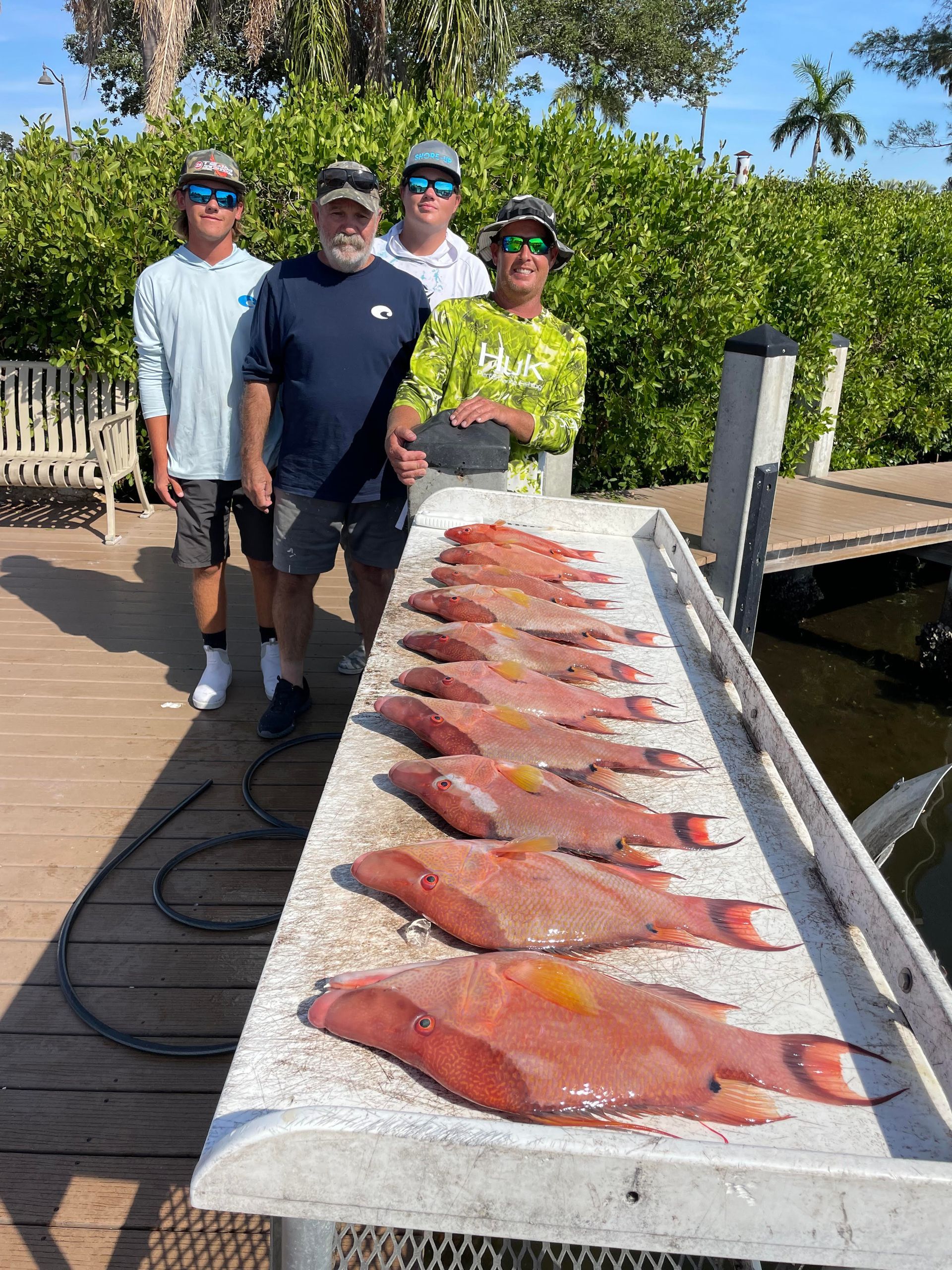 A group of men are standing next to a table full of fish.