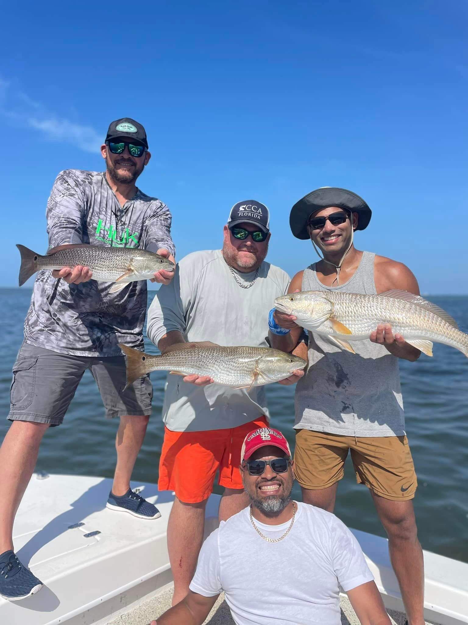 A group of men are standing on a boat holding fish.