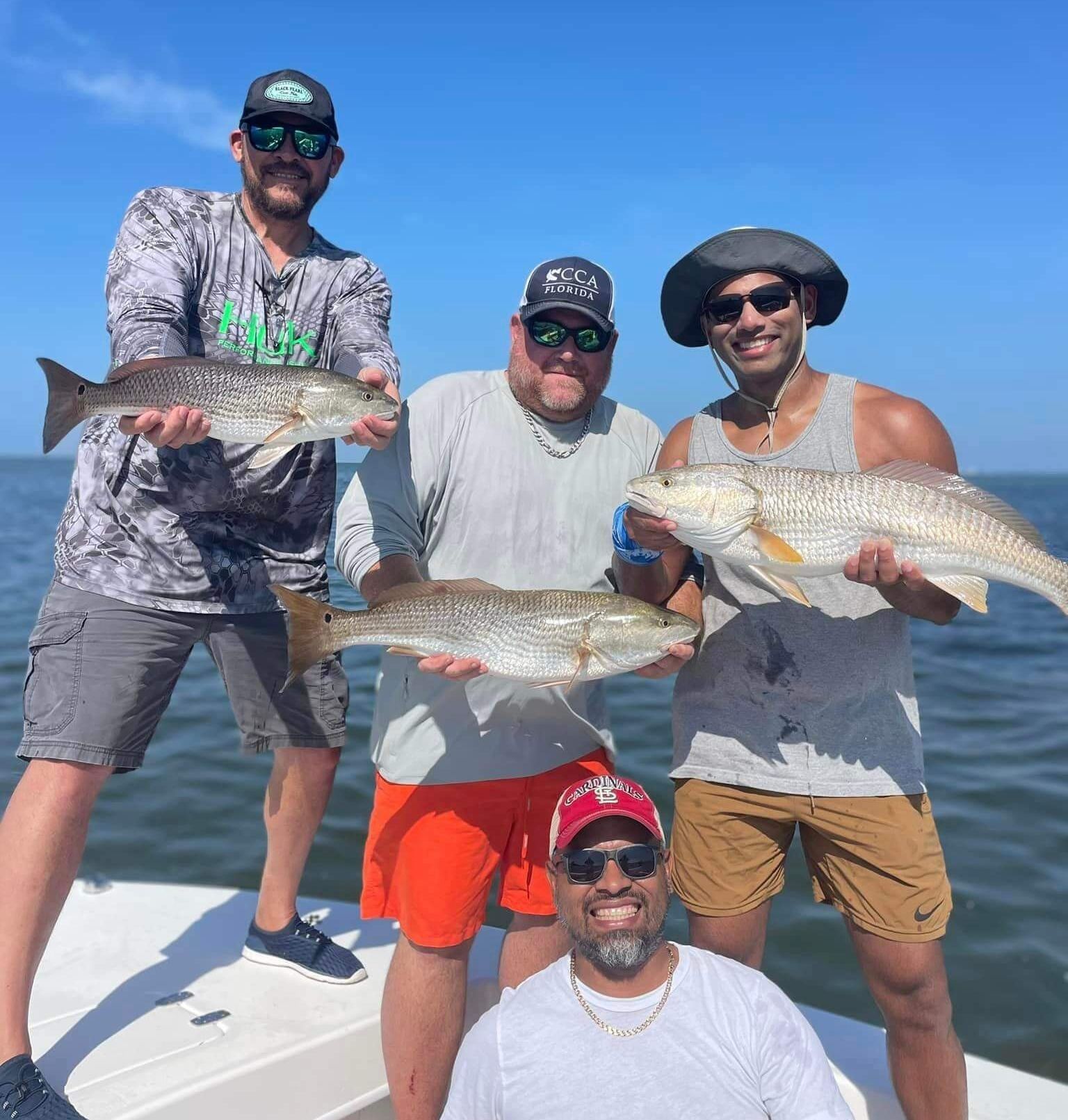 A group of men are standing on a boat holding fish.