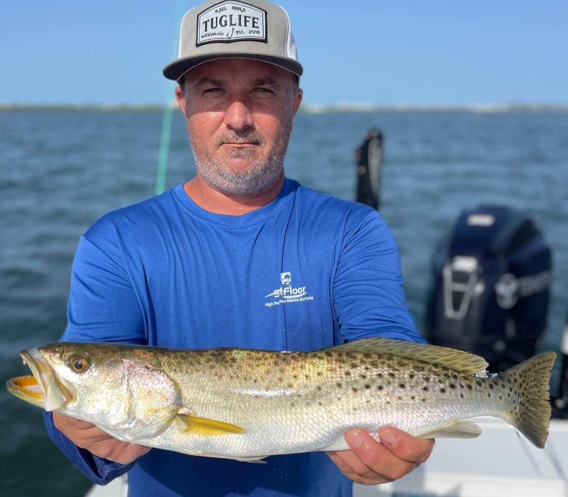 A man is holding a large fish on a boat.