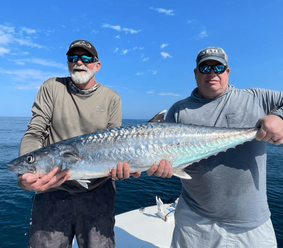 Two men holding a large fish on a boat