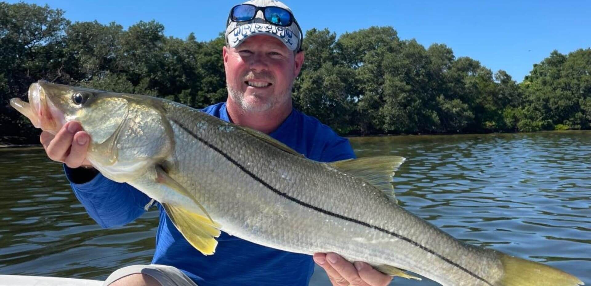 A man is holding a large fish in his hands on a boat.