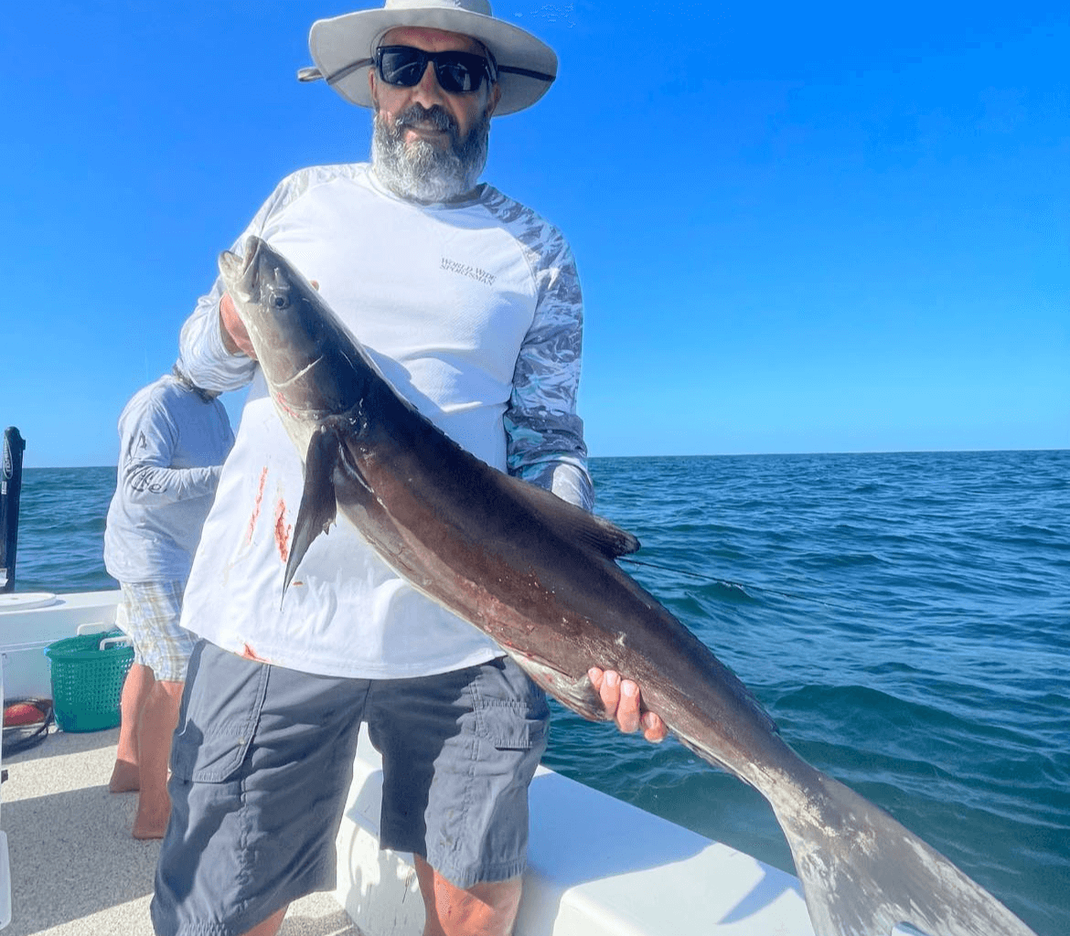 A man is holding a large fish on a boat.