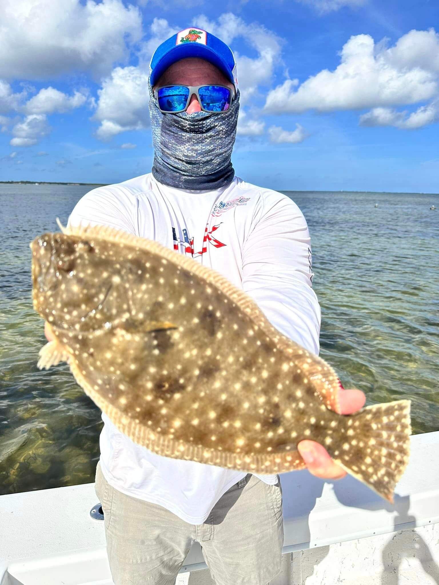 A man is holding a large fish in his hands on a boat.