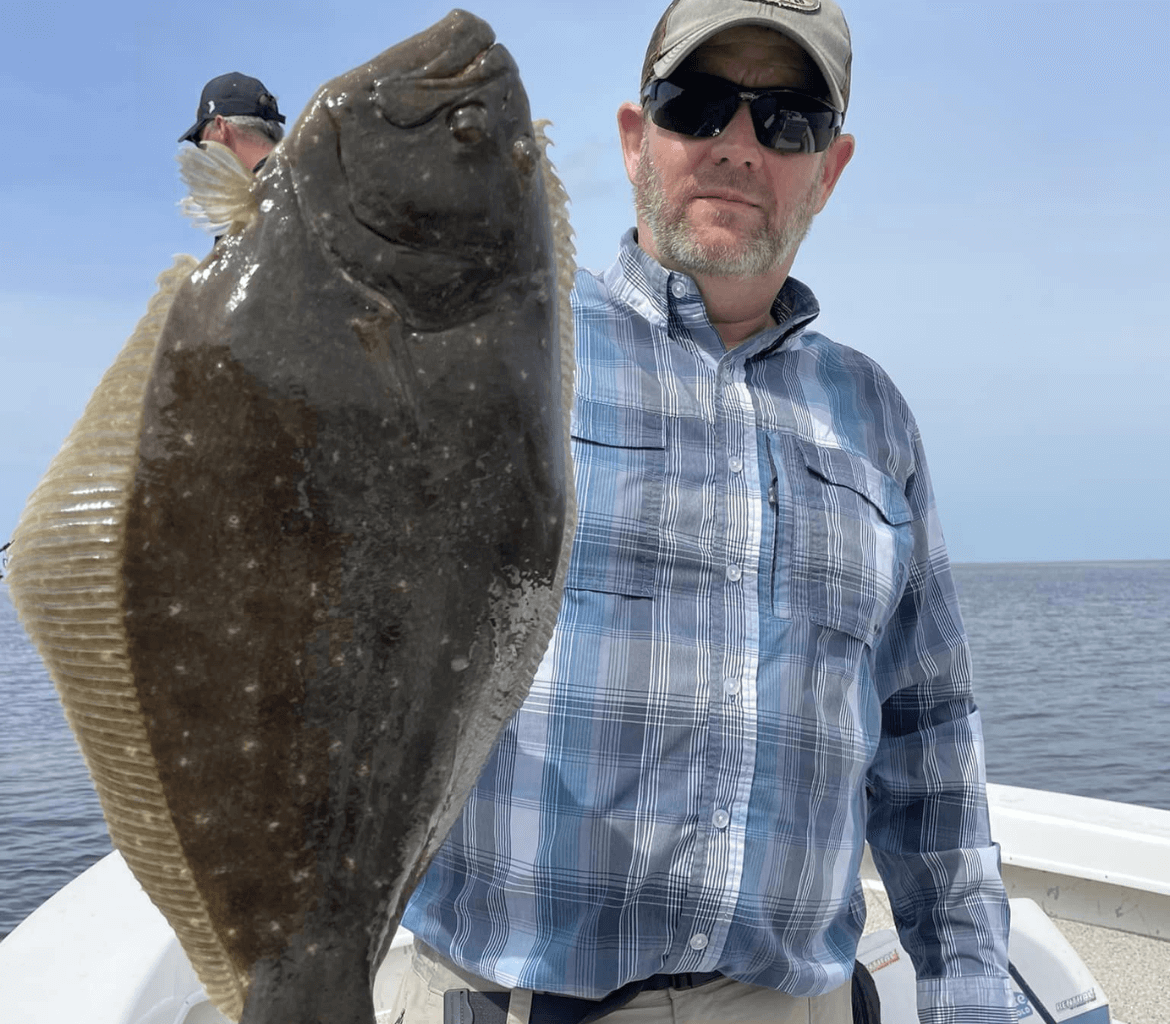 A man is holding a large fish on a boat.