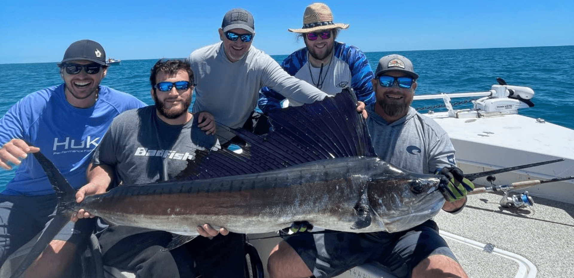 A group of men are holding a large sailfish on a boat.