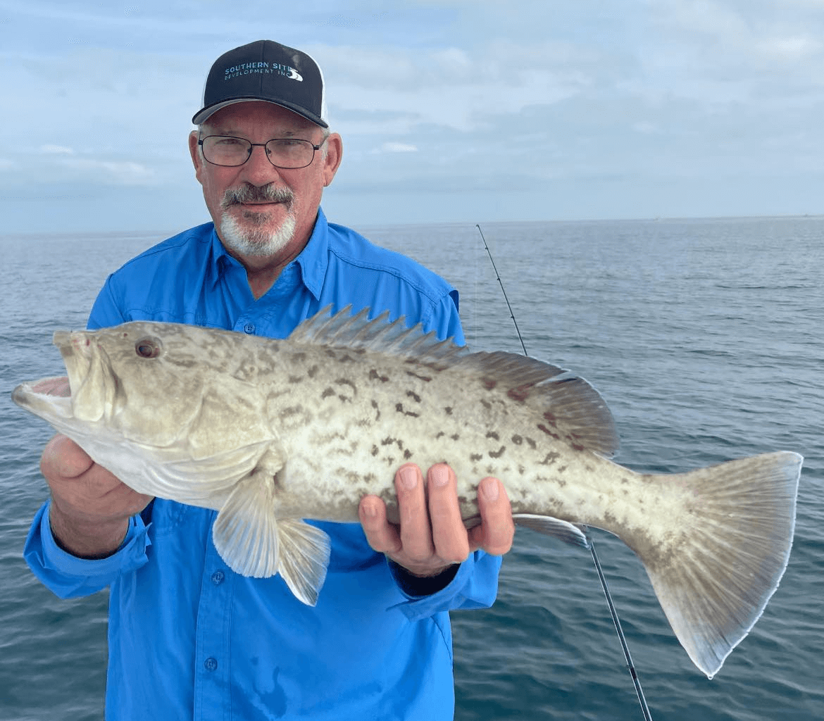 A man in a blue shirt is holding a large fish