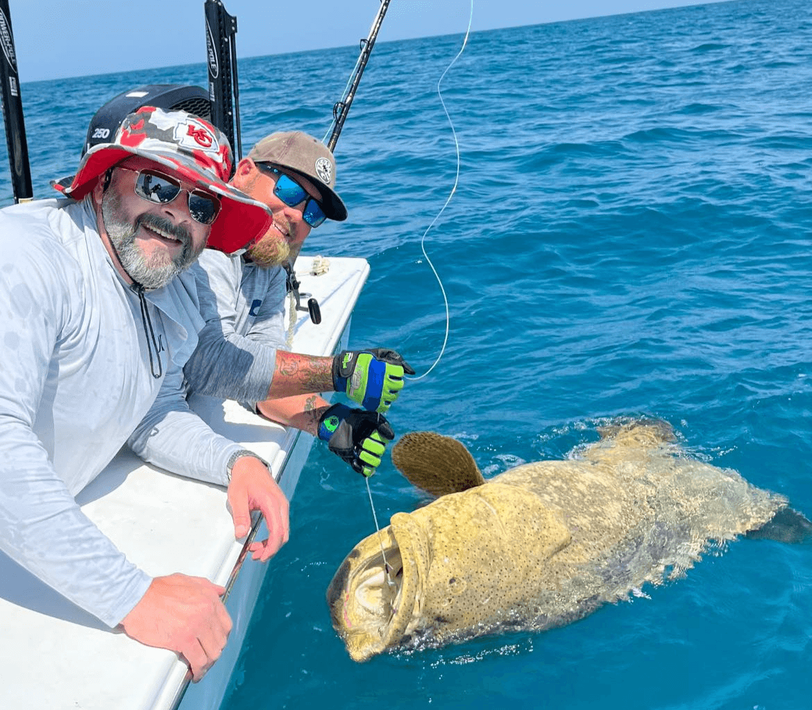 Two men are fishing in the ocean with a large fish.