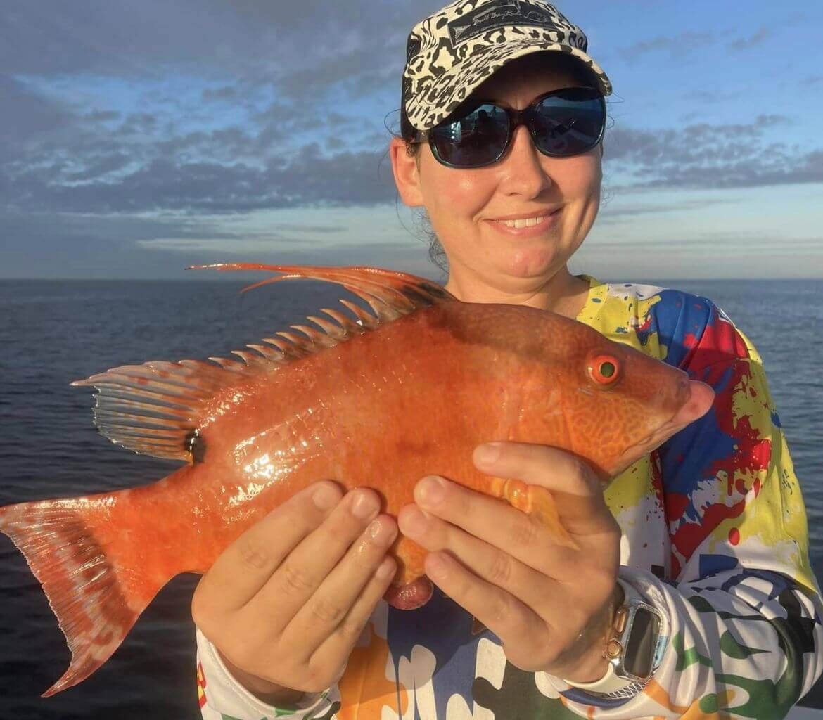 A woman is holding a large red fish in her hands