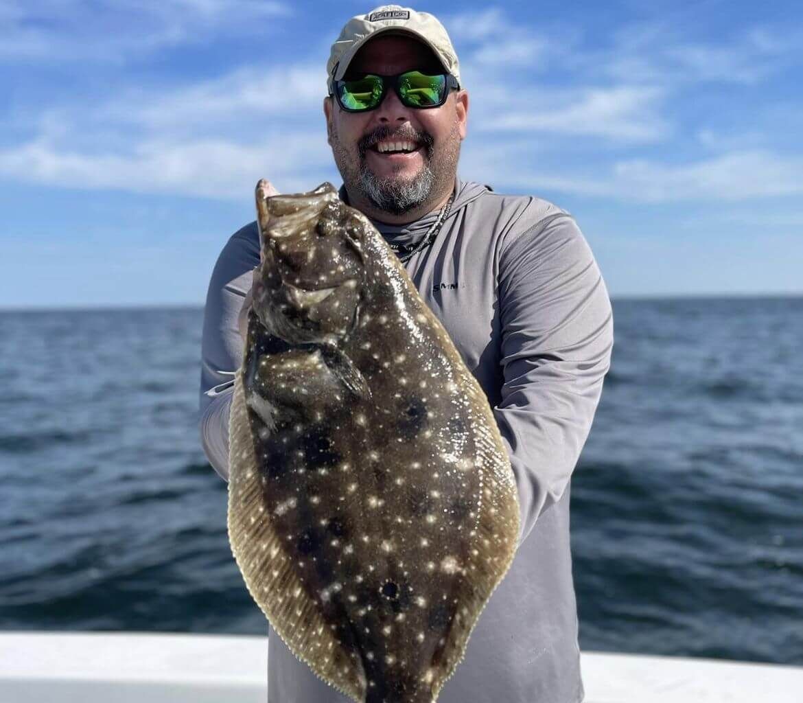 A man is holding a large fish in his hands on a boat.