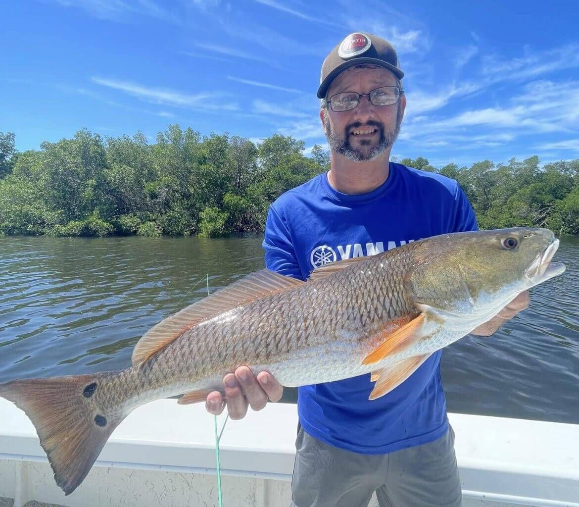 A man is holding a large fish on a boat.