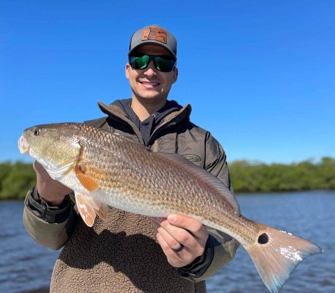 A man is holding a large red fish in his hands