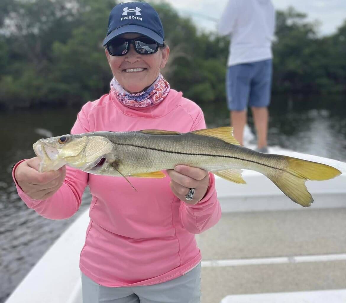 A woman is holding a large fish on a boat.