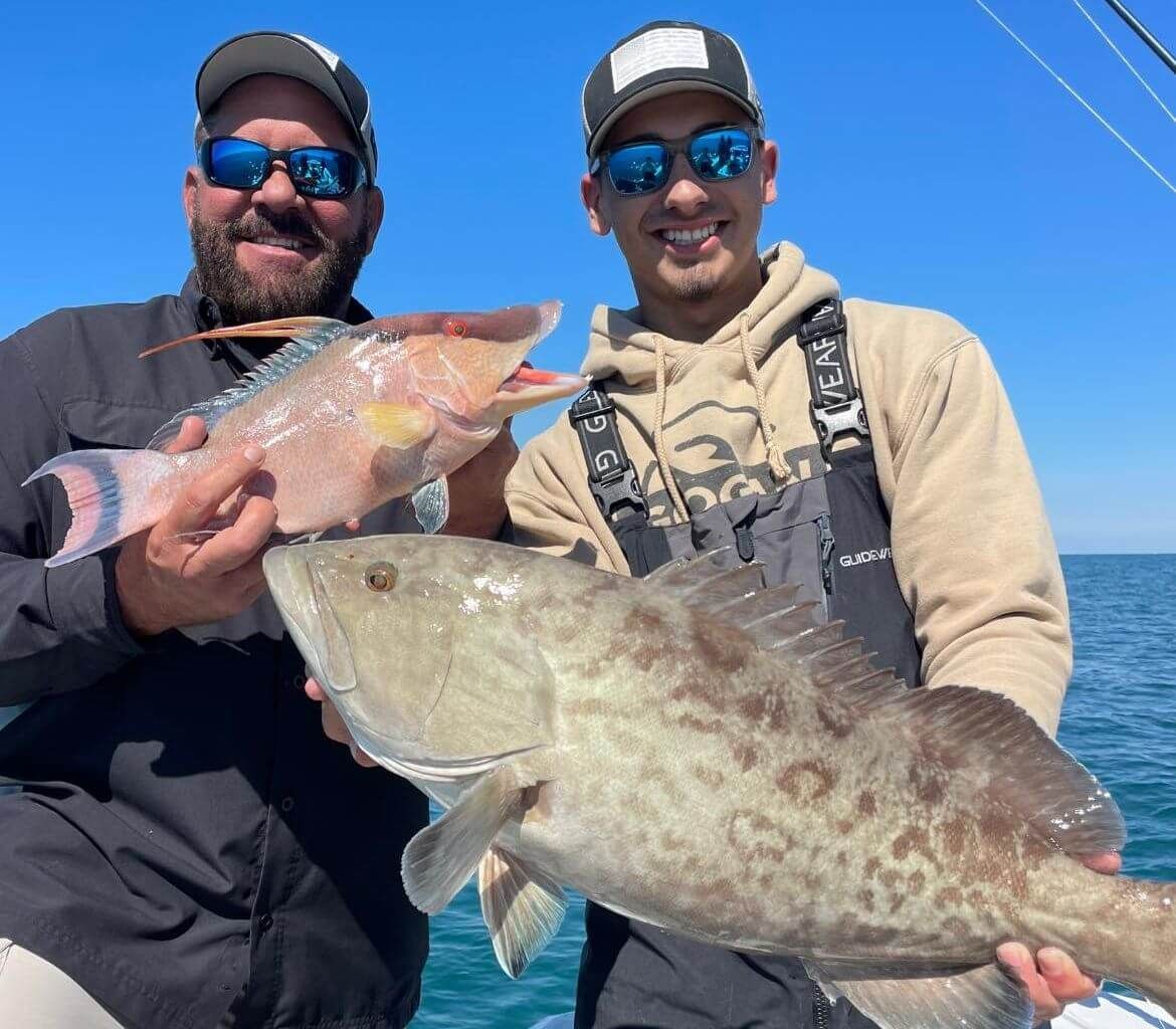 Two men are holding fish in their hands on a boat