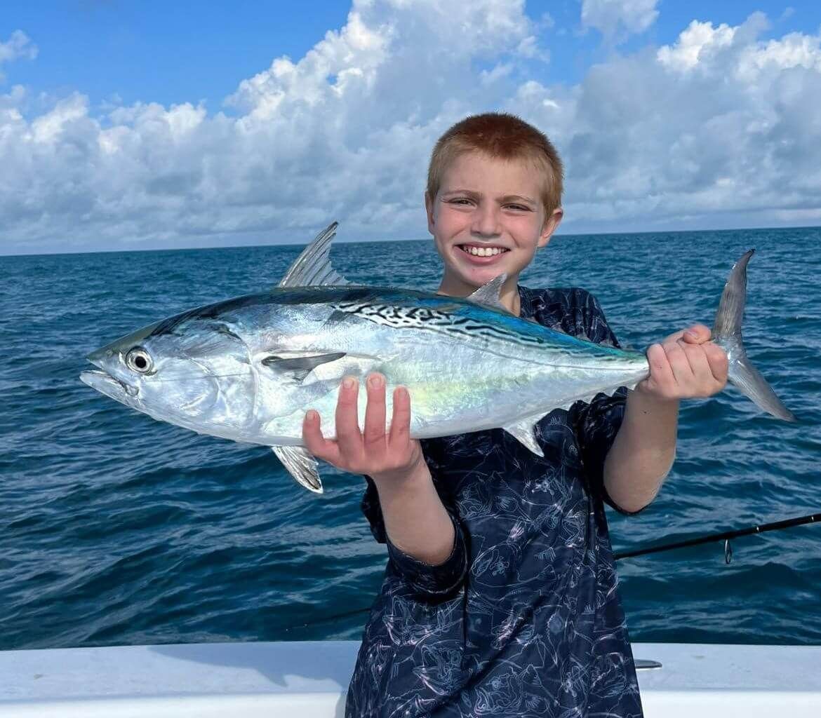 A young boy is holding a large fish in his hands