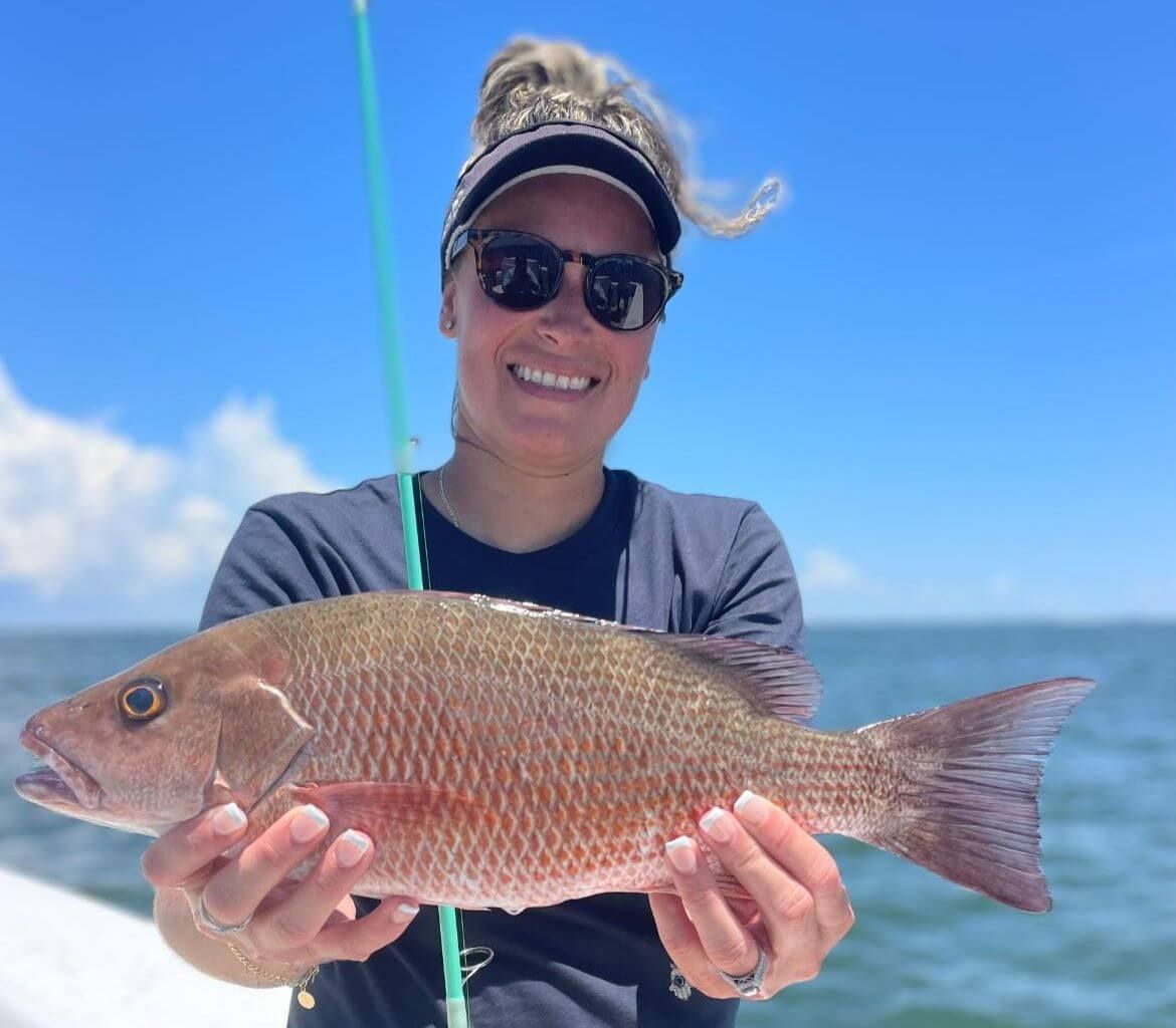 A woman is holding a fish in her hands and smiling