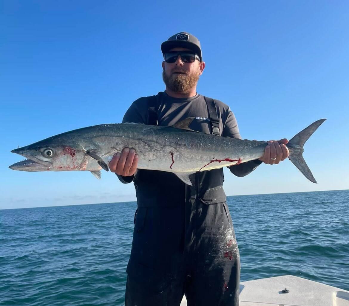 A man on a boat holding a large fish