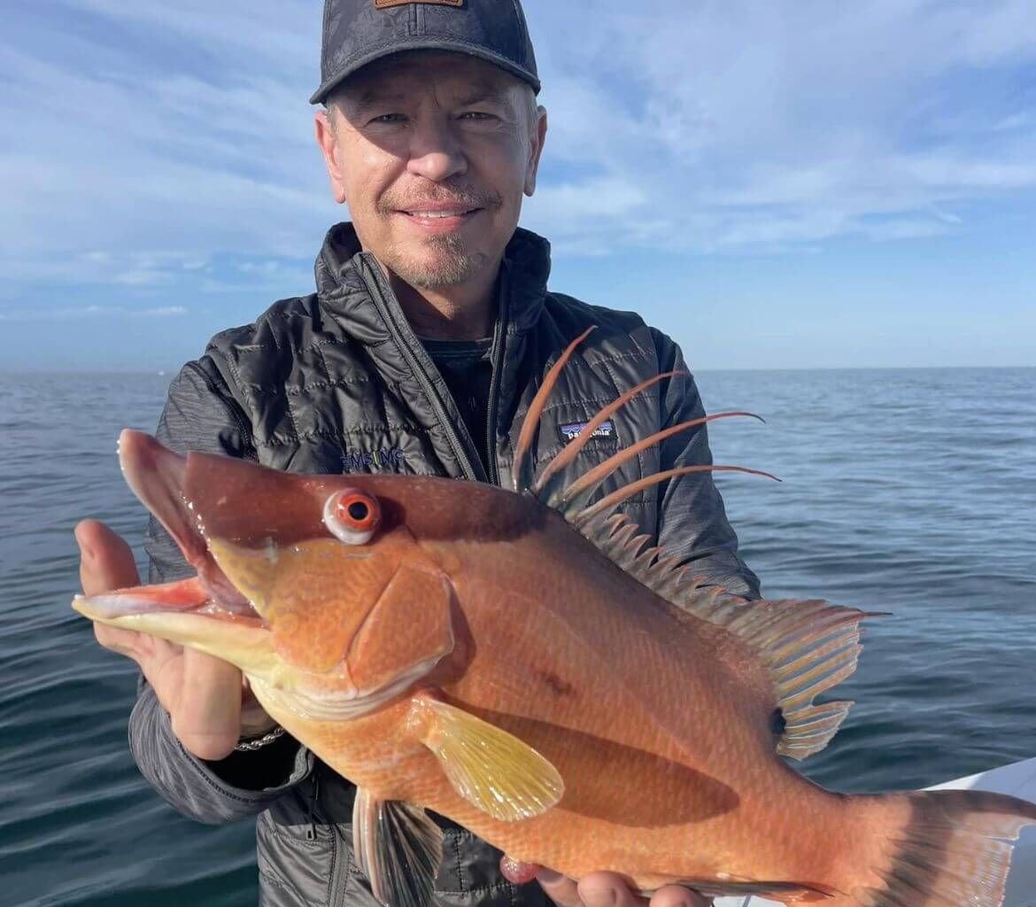 A man is holding a large red fish in his hands.