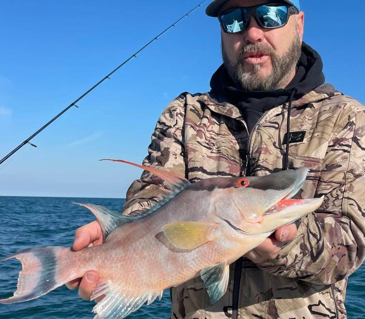 A man in a camo jacket is holding a large fish