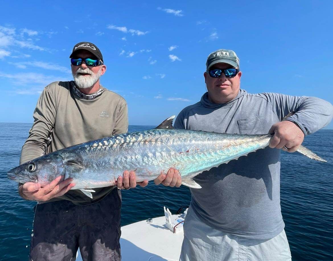 Two men are holding a large fish on a boat.