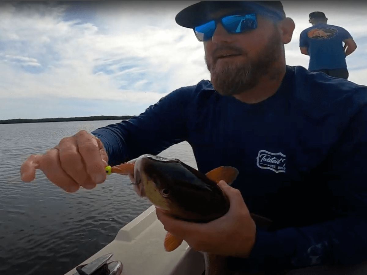 A man in a blue shirt is holding a fish on a boat | Captain William Wise