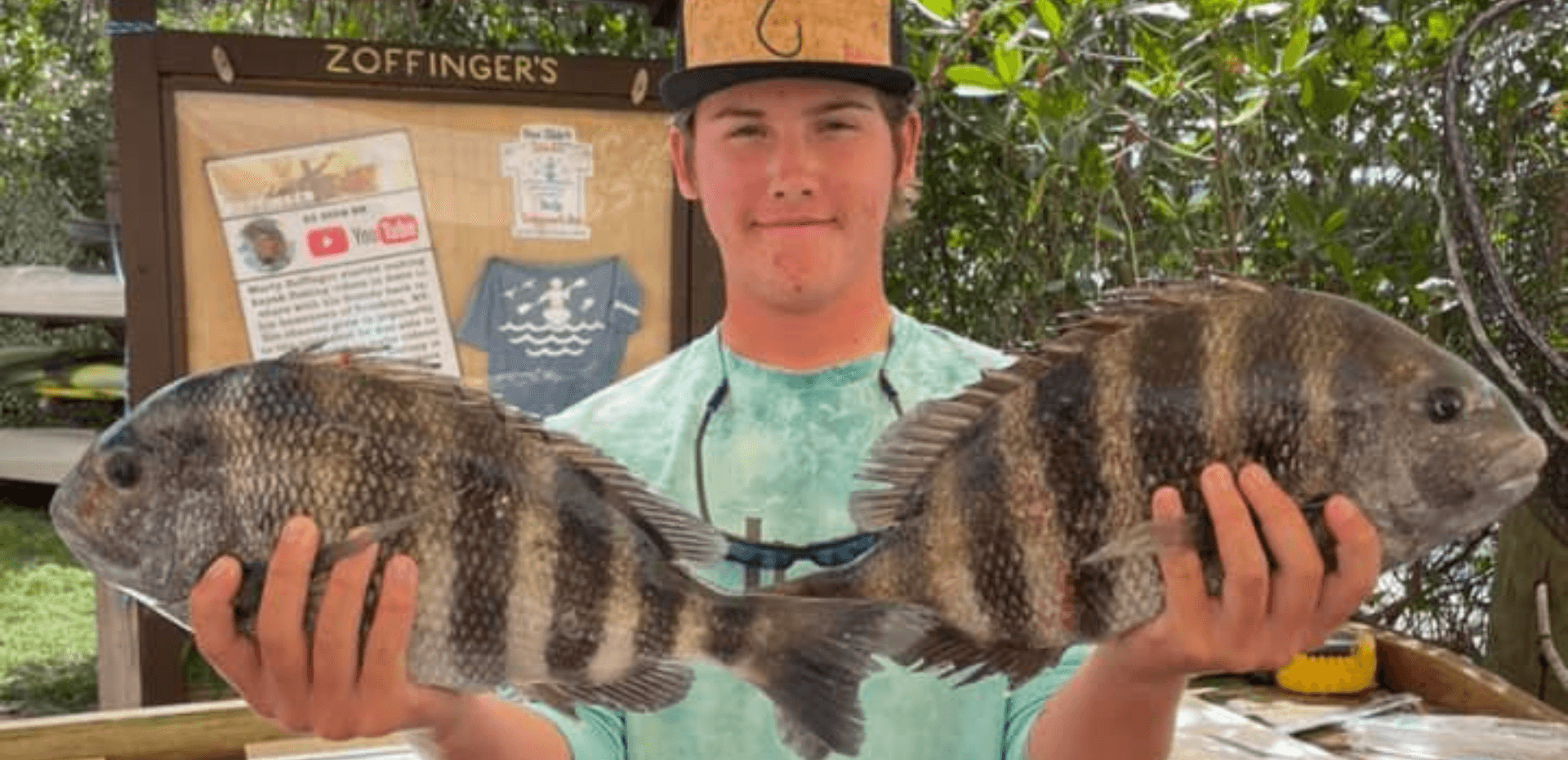 A young man is holding two large fish in his hands.