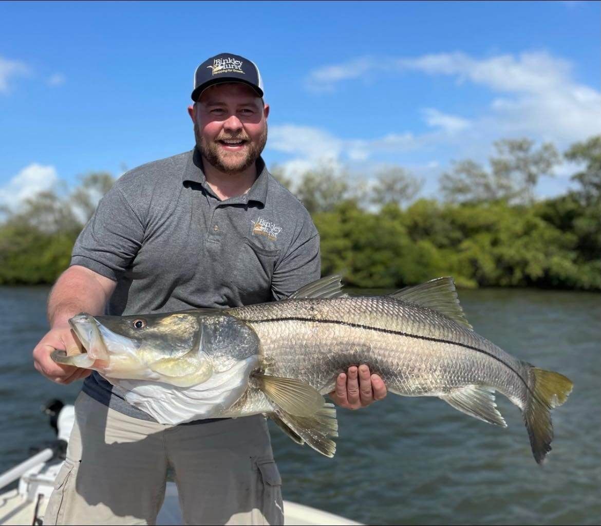 A man is holding a large fish in his hands on a boat.