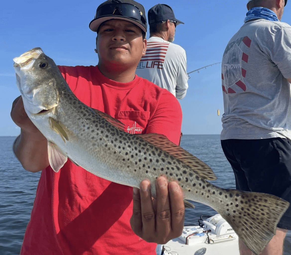 A man in a red shirt is holding a fish in his hands