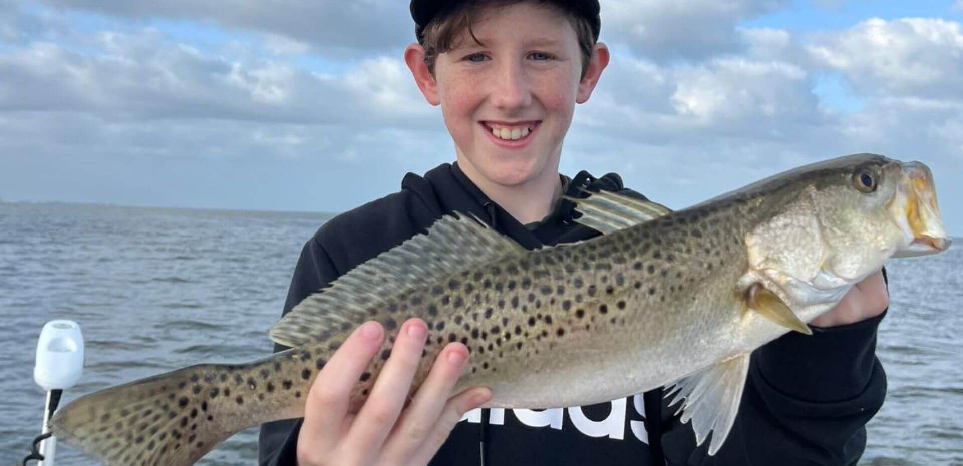 A young boy is holding a large fish in his hands.